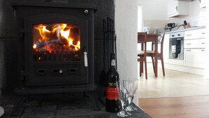 Een houtkachel met een fles wijn en glazen op een tafel.