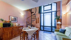 Ein Essbereich mit Tisch für vier Personen, einer Wendeltreppe und einem großen Fenster mit satinierten Glasscheiben.