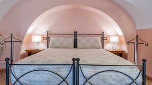 Ein Bett mit Metallgestell, zwei Nachttische mit Lampen und ein Wandbogen.