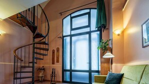 Ein großzügiger Wohnbereich mit Wendeltreppe, einem großen Fenster und einem grünen Sofa.