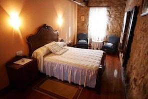 Classic design room with a large bed, bedside tables, and a small reading nook by the window.