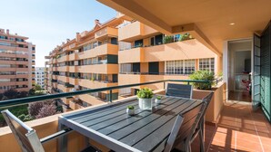 A balcony with a table and chairs, potted plants, and a view of neighboring buildings. - Cascais Park (Cascais)
