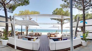 Un espacio de estar al aire libre cubierto con sofás blancos y sombrillas, con vistas al mar.