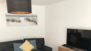 A living room with a sofa, a coffee table, a TV, and a wooden cabinet. - Peaceful Retreat, Sovereign Harbour, Eastbourne - FREE WELCOME PACK (Eastbourne)