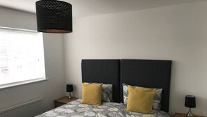 A bedroom with a bed, two bedside tables, a window, and a hanging light fixture. - Peaceful Retreat, Sovereign Harbour, Eastbourne - FREE WELCOME PACK (Eastbourne)