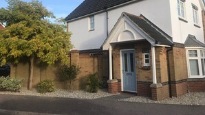 A two-story building with a white facade, a dark roof, and a small porch with a blue door. - Peaceful Retreat, Sovereign Harbour, Eastbourne - FREE WELCOME PACK (Eastbourne)