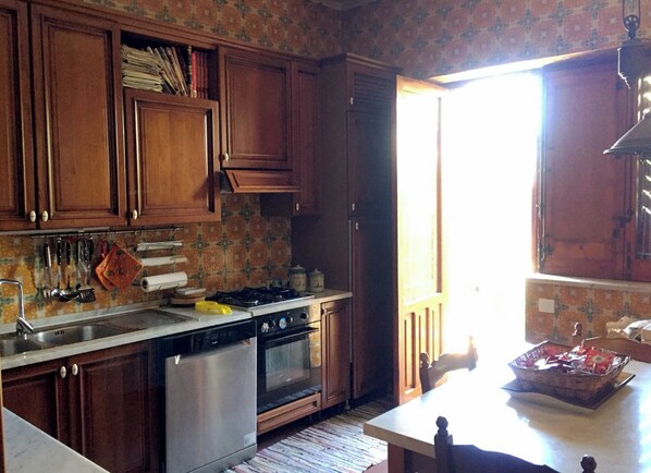 A kitchen with wooden cabinets, a stove, oven, and a dishwasher. - Relaxing at Villa Maria (Terrasini)