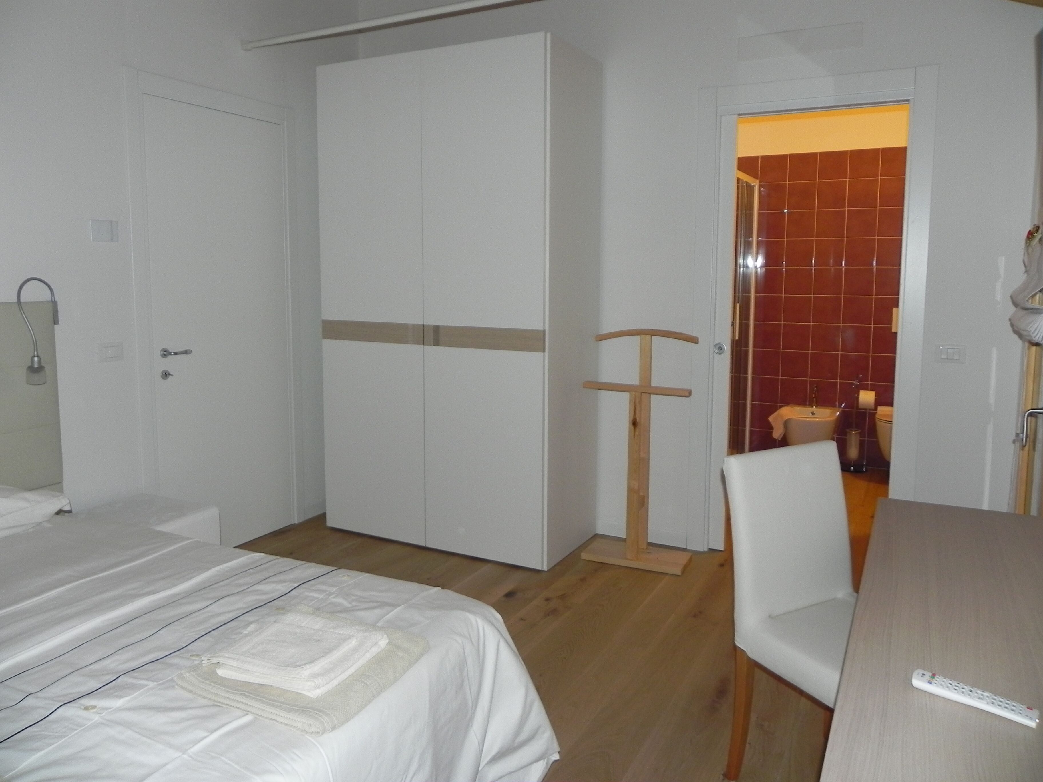 A bedroom with a bed, a wardrobe, a chair, and a desk.