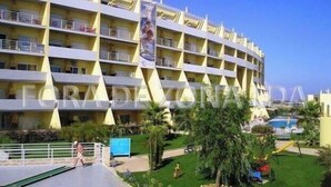 Ein mehrstöckiges Hotel mit Poolbereich, Kinderspielplatz und gepflegtem Rasen.