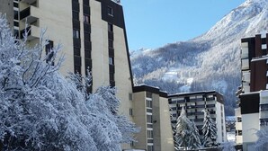 Un aparcamiento cubierto de nieve con un edificio de diseño moderno y montañas al fondo.