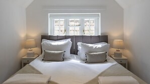A bedroom with a large bed, two bedside lamps, and a window with blinds.