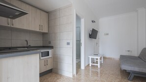Une cuisine moderne équipée d’un four à micro-ondes encastré, d’une petite table blanche et d’un canapé gris dans un vaste espace de vie.