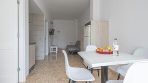 Une cuisine moderne avec des meubles blancs, une table à manger avec des chaises et un petit tabouret.