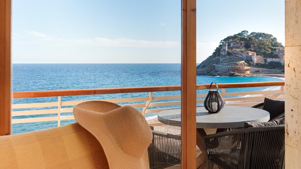 Varanda com vista para o mar e uma colina com edifícios.