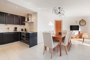 A modern kitchen with dark cabinets, a built-in oven, and a dining area with a wooden table and chairs. - INCREDIBLE APARTMENT WITH AMAZING VIEWS (Tossa de Mar)