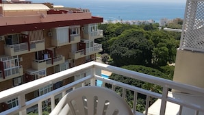A balcony with a white plastic chair and table, overlooking a residential area with a view of the sea. - Studio apartment With Shared Pool, Garden And Kiosk Serving alcohol & ices/sweet (Benalmádena)