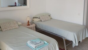 A bedroom with two single beds, a ceiling fan, a bedside table with a lamp, and a mirror on the wall. - Studio apartment With Shared Pool, Garden And Kiosk Serving alcohol & ices/sweet (Benalmádena)
