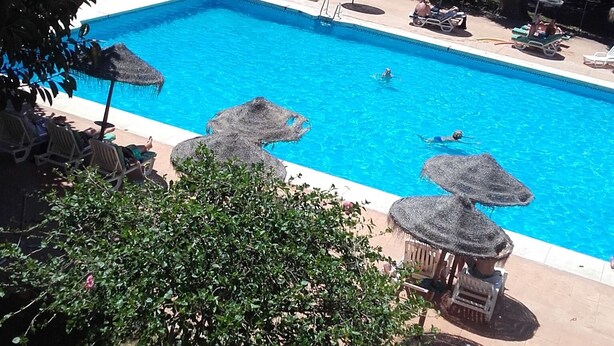 A swimming pool with lounge chairs and umbrellas, surrounded by greenery. - Studio apartment With Shared Pool, Garden And Kiosk Serving alcohol & ices/sweet (Benalmádena)