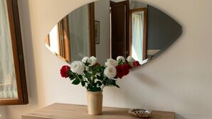 Un aparador de madera con un jarrón de flores blancas y rojas, un espejo y un pequeño plato encima.
