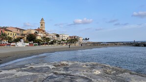 A coastal town with a prominent tower, sandy beach, and rocky shoreline.