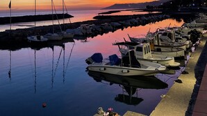 A marina with boats docked at calm waters during sunset.