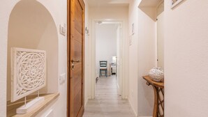 A hallway with a wooden door, a chair, and a small table with a decorative item. - Marco's Stylish Home: in the hearth of Cagliari (Cagliari)