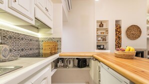 A compact kitchen with white cabinetry, a patterned backsplash, and a wooden countertop. - Marco's Stylish Home: in the hearth of Cagliari (Cagliari)