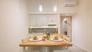 A kitchen with white cabinets, a wooden dining table, and two chairs. - Marco's Stylish Home: in the hearth of Cagliari (Cagliari)