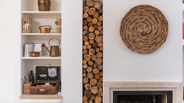 A fireplace with a woven wall hanging, a shelf with a copper pot, and a stack of logs. - Marco's Stylish Home: in the hearth of Cagliari (Cagliari)