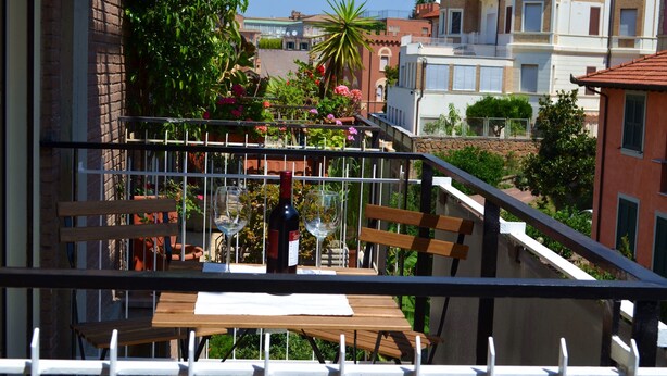 A balcony with a table, two wine glasses, and a bottle of wine.