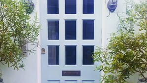 A white door with nine panels, flanked by two potted plants and two wall-mounted lanterns. - Coastal City Coach House on Plymouth's historic hoe (Plymouth)