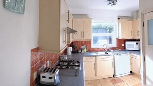 A kitchen with a stove, toaster, microwave, sink, and cabinets. - Coastal City Coach House on Plymouth's historic hoe (Plymouth)