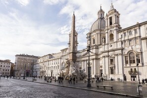 A historic square with a prominent fountain, classical architecture, and a cobblestone street. - Stay in Rome Apartments Central Navona Sq (Roma)