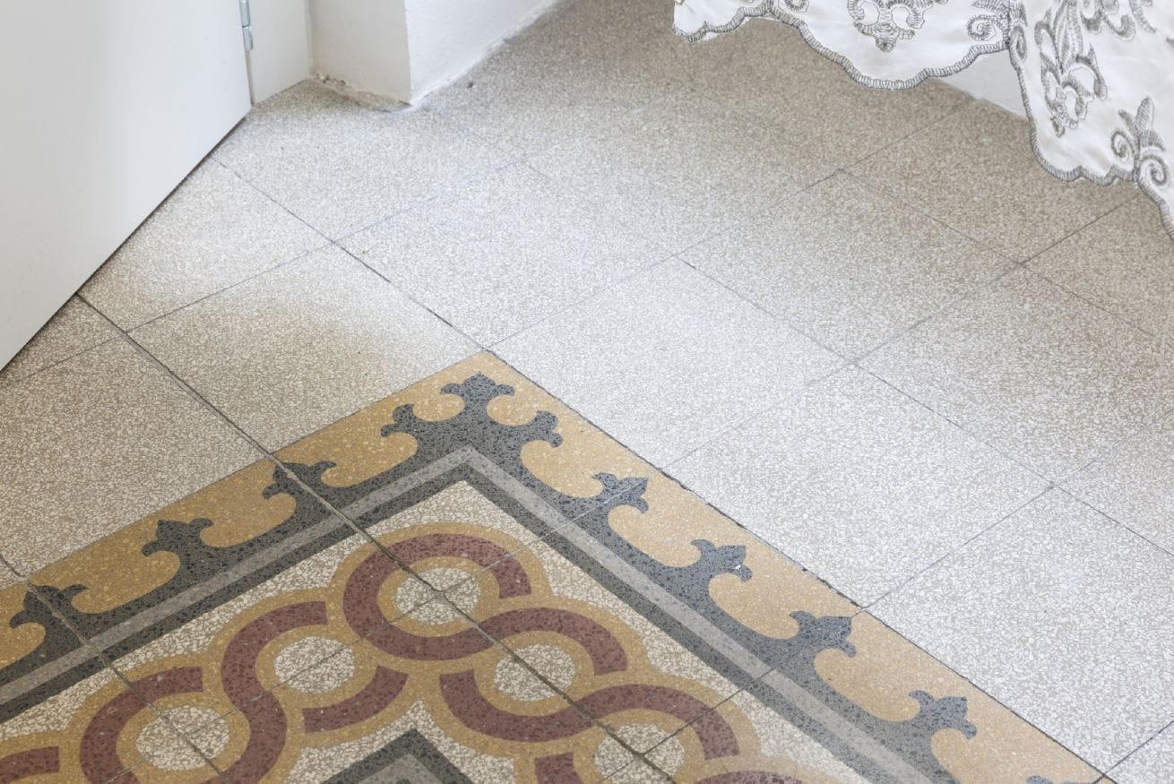 Ein gemustertes Teppich auf Fliesen, eine weiße Wand und ein Tisch mit einer gemusterten Tischdecke.