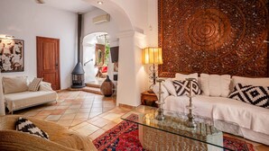 A living room with a sofa, a glass coffee table, a fireplace, and a decorative wall panel.