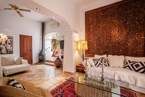A living room with a sofa, a glass coffee table, a fireplace, and a decorative wall panel.