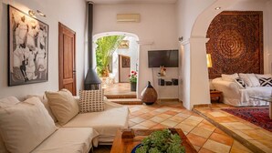 A living room with a sofa, a coffee table, a TV, and a decorative wall.