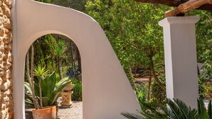 An outdoor patio area with a white archway, a wooden beam, and potted plants.