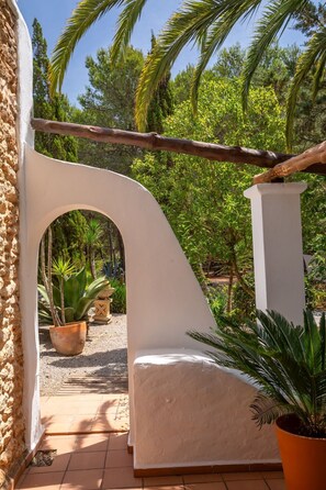 An outdoor patio area with a white archway, a wooden beam, and potted plants.
