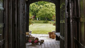 An open doorway leading to a garden with a lawn, potted plants, and a wicker basket on the floor.