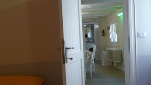 Um quarto com uma cama, uma porta que dá para uma cozinha e um corredor.