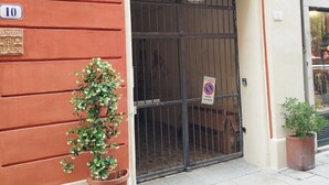 Um edifício com fachada vermelha, uma placa com o número 10, entrada com grades e um vaso de planta.