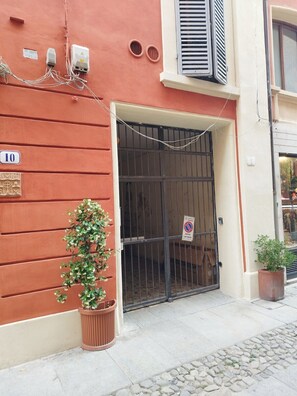 A building with a red facade, a number '10' sign, a barred entrance, and a potted plant.
