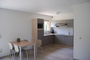 Uma cozinha moderna com mesa e cadeiras de madeira, micro-ondas e pia.