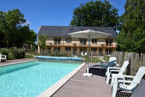 Piscina com espreguiçadeiras e deck de madeira.