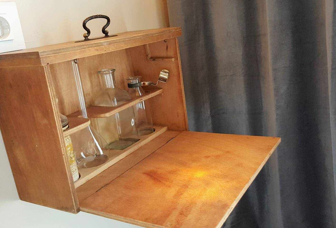 Ein Holzkabinent mit Regalen, voll mit Glasbehältern und Metallboxen.