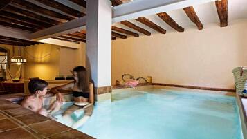 Una piscina interior con vigas de madera y suelo de baldosas.