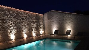 A swimming pool with lounge chairs and a stone wall.