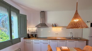 Een moderne keuken met witte kastjes, een houten aanrecht, een ingebouwde kookplaat en een eettafel met stoelen.
