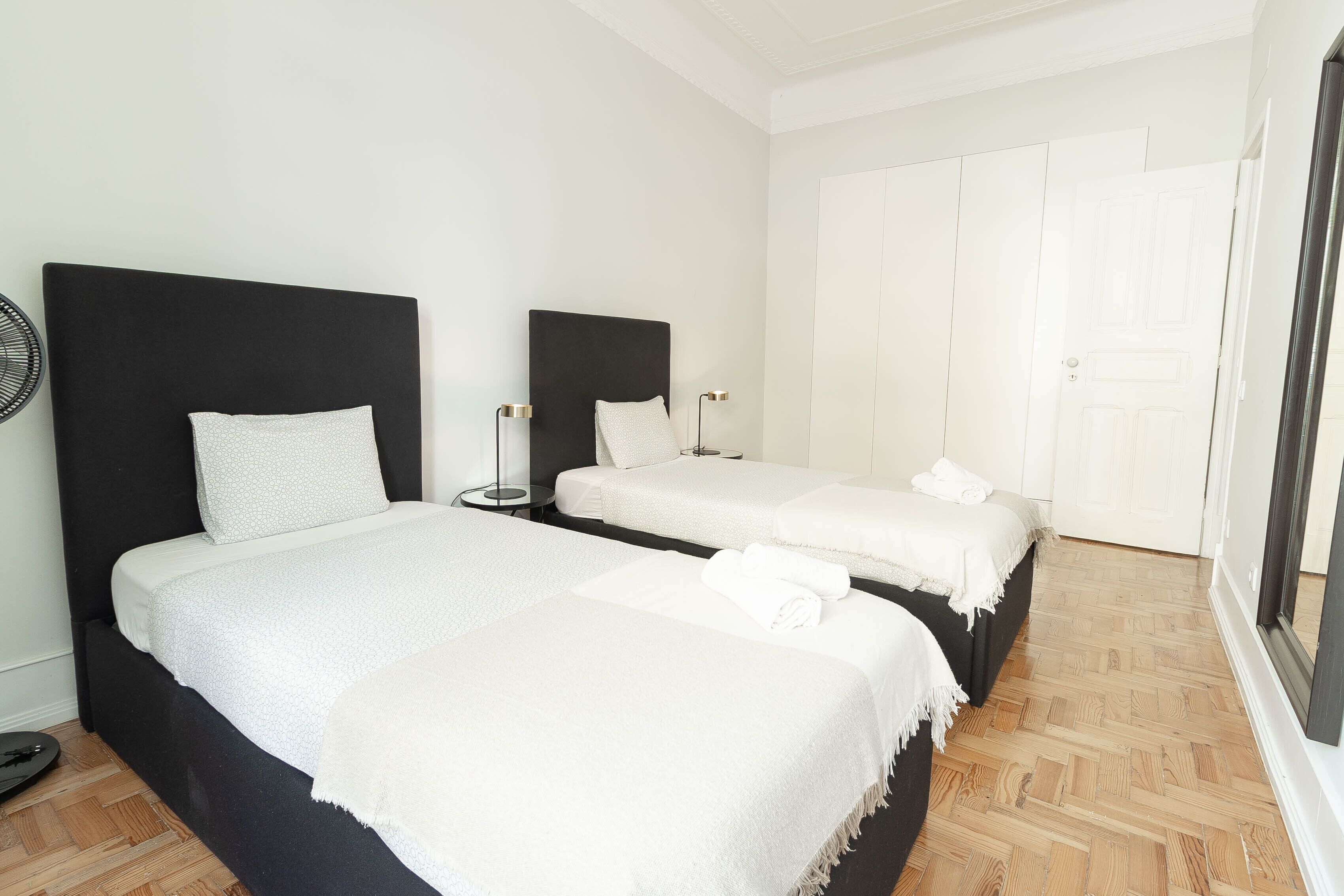 Une chambre d’hôtel avec deux lits, un grand miroir et une armoire.